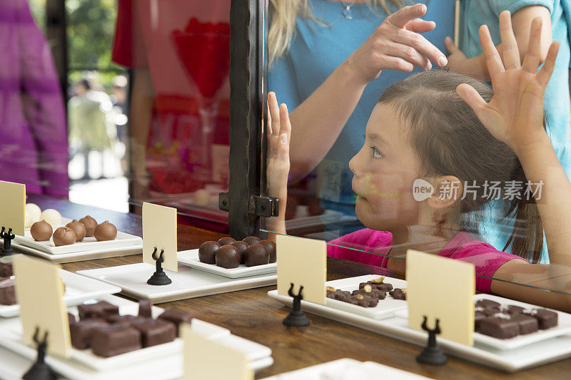 年轻兴奋的女孩在糖果店看巧克力松露