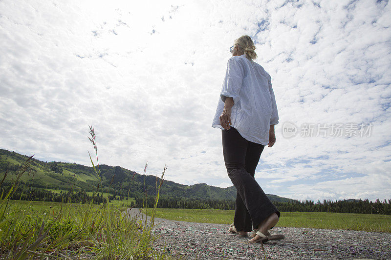 女人沿着乡间小路走向山丘