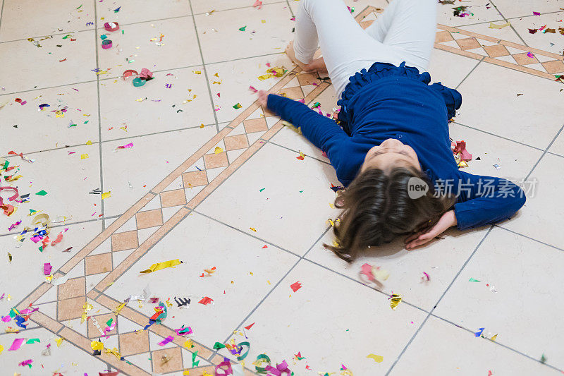 小女孩躺在撒满五彩纸屑的地板上