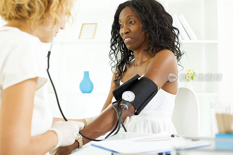医生给中年妇女测血压。