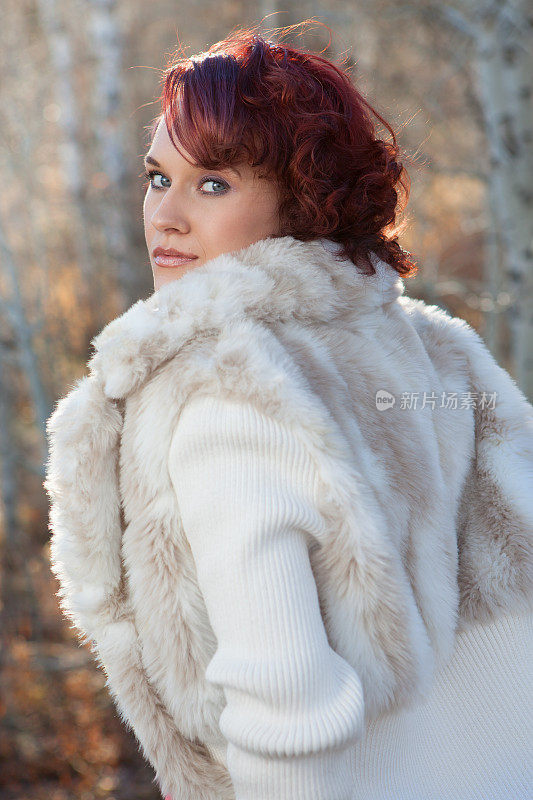 森林里穿着白色毛皮大衣的年轻女子