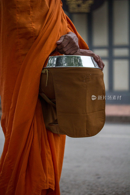 琅勃拉邦的一名僧人拿着行乞的碗在小路上