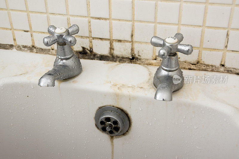水龙头后面的灌浆和瓷砖上有浴室污垢和霉菌