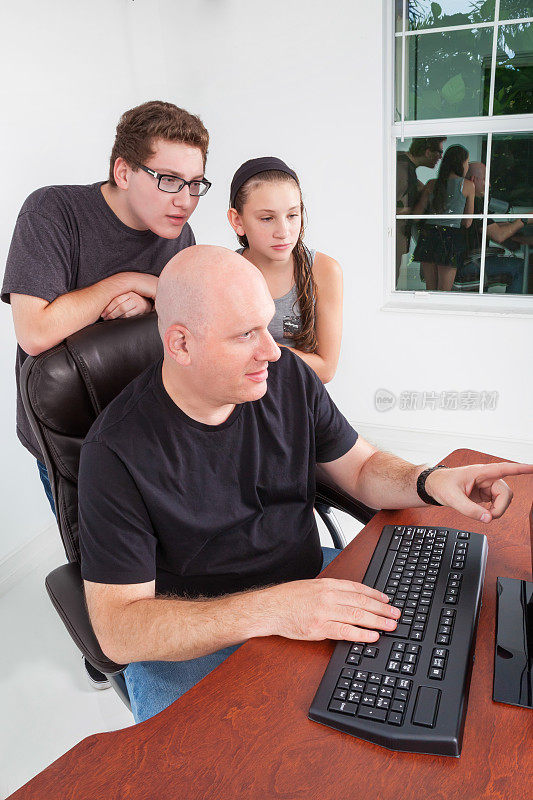 父亲在电脑上向他的孩子们指出一些东西