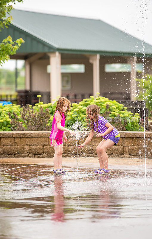 两个女孩在水花公园的喷泉里玩耍