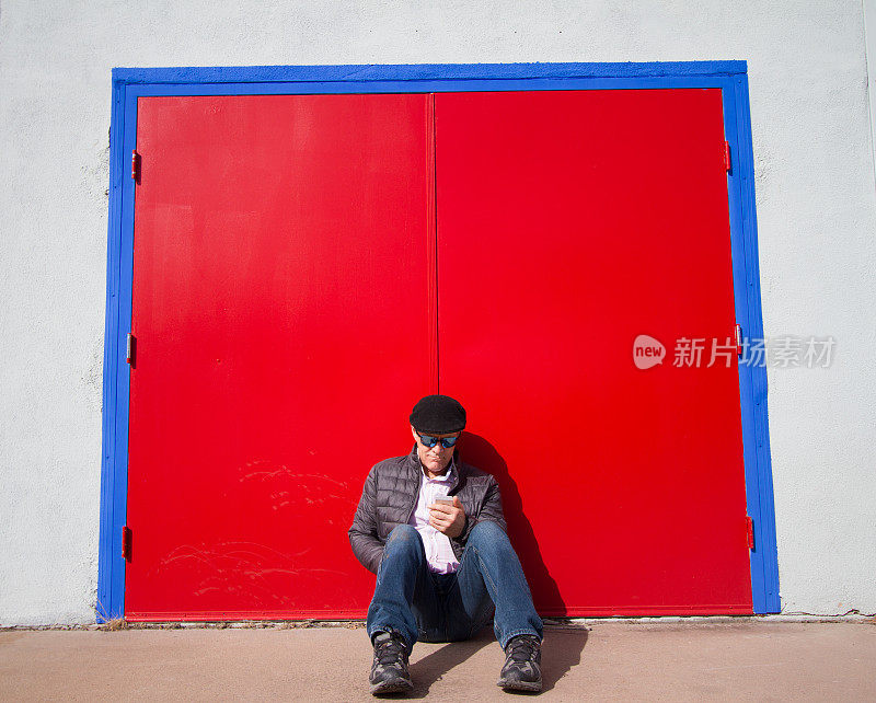 男人坐在那里看智能手机，发短信，大红门