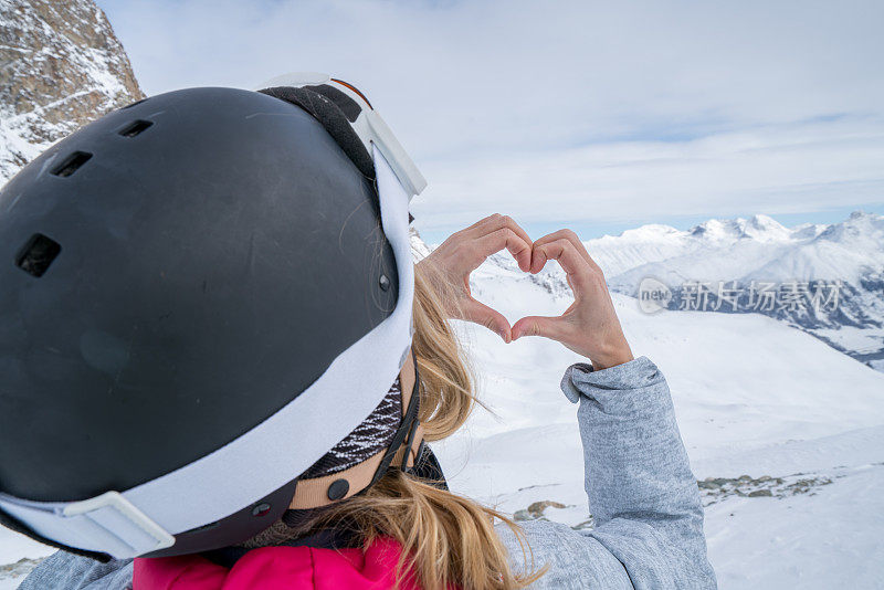 年轻女子在滑雪坡上做心形