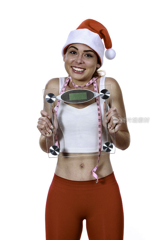 体重减轻的年轻女子与秤和圣诞帽