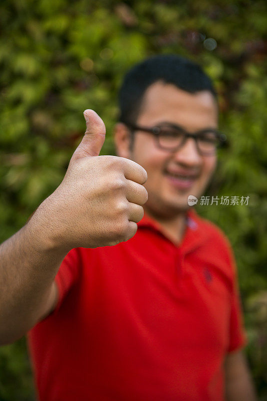 微笑的年轻人竖起大拇指的肖像
