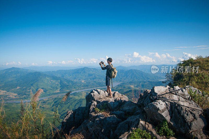 年轻的旅行者站在山上望着夕阳。