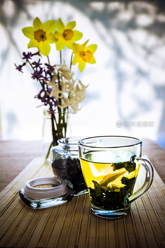 木桌上的玻璃茶杯里装着鲜花和茶叶