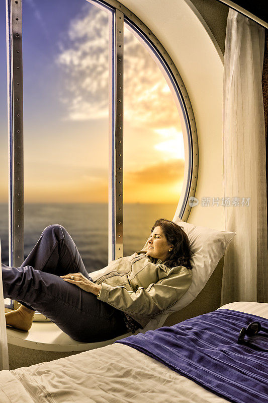 日落时分，西班牙裔女子在游艇客舱的窗户上休息
