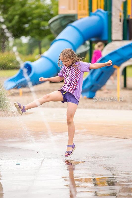小女孩在户外水花公园的喷泉里玩耍