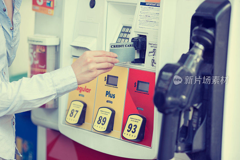 一个女人在加油站刷信用卡。