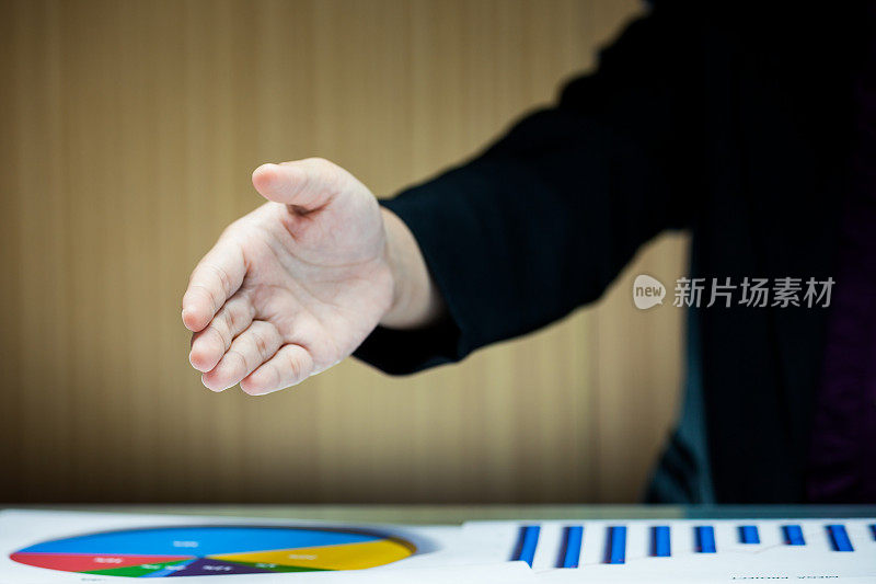 一个商人的手握在办公桌上方的握手特写