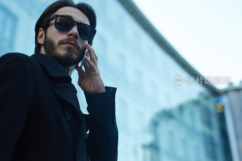 英俊的男人在城市的街道上使用电话
