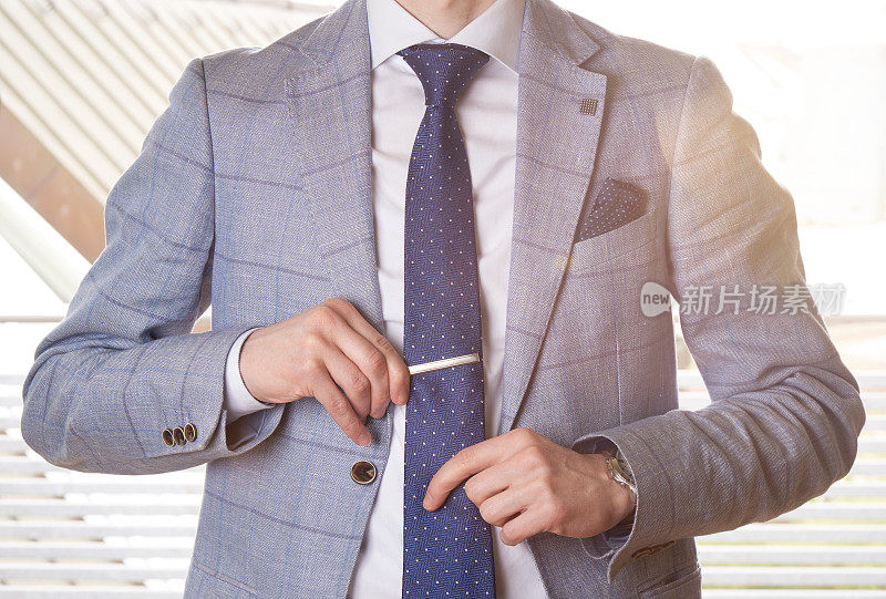 一个面目全非的商人通过调整领带夹来摆正领带。带有镜头光晕效果的背光。