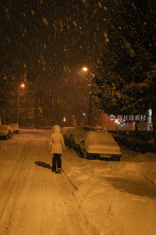 一个女人在下雪的晚上散步