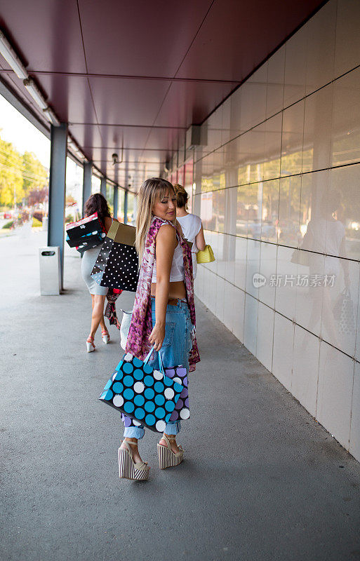 三个漂亮的女孩拿着购物袋在商店里