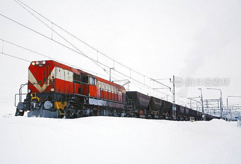 白色风景与红色火车头和铁矿石货车在雪