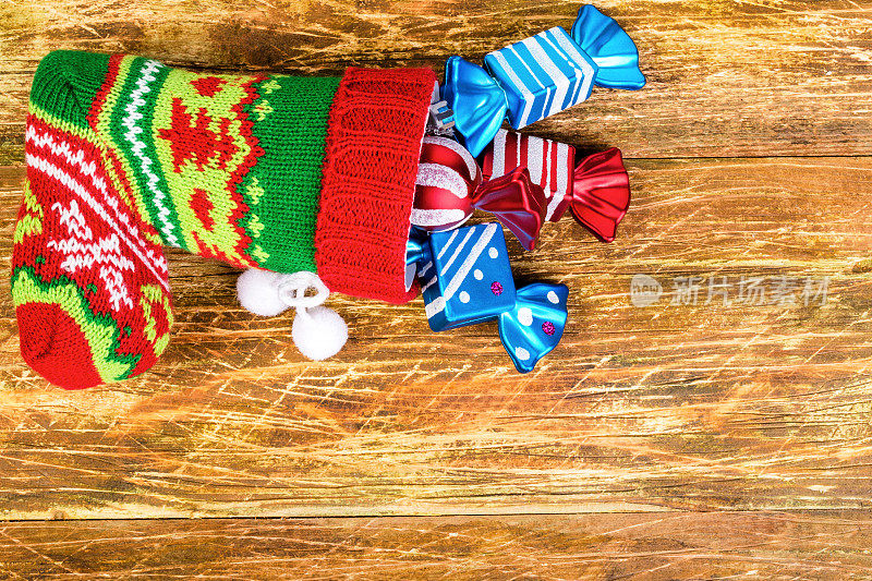 用圣诞袜做成的圣诞作文。圣诞袜躺在一个被刮花的木头表面上。装饰糖果从上面伸出来。快乐圣诞的概念。前视图。