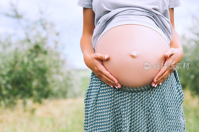 特写怀孕的肚子在自然，户外，复制空间。
