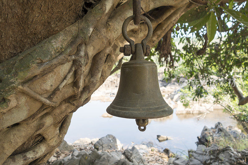 在树林里，挂在印度教祭坛上方树上的铜钟