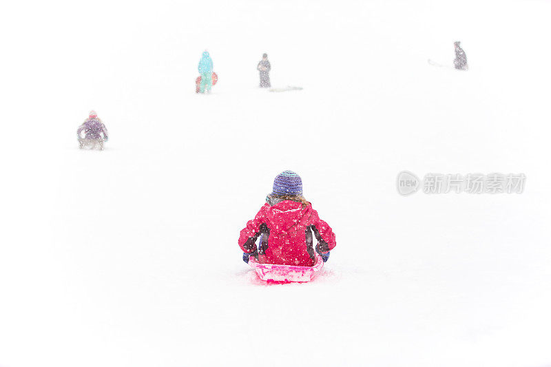 女孩在冬天滑下山坡