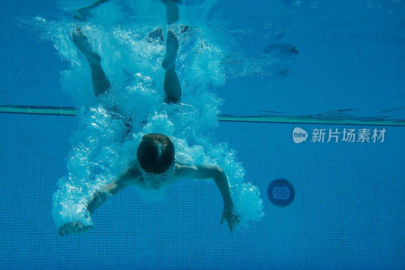 小男孩正在游泳池里跳水