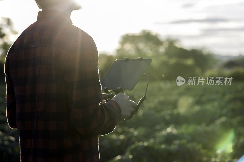 农人飞行员在日落时使用无人机遥控