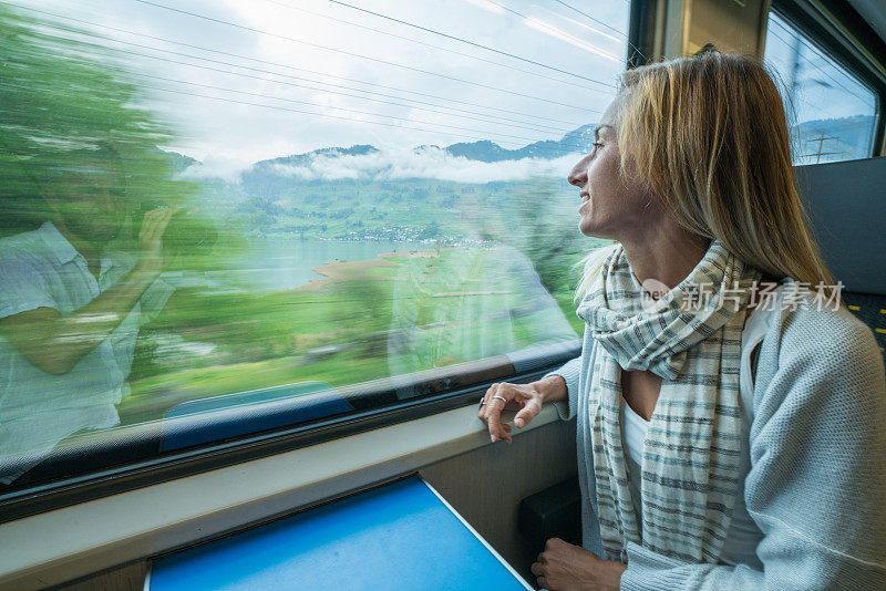 在瑞士乘火车旅行的年轻女子透过窗户看