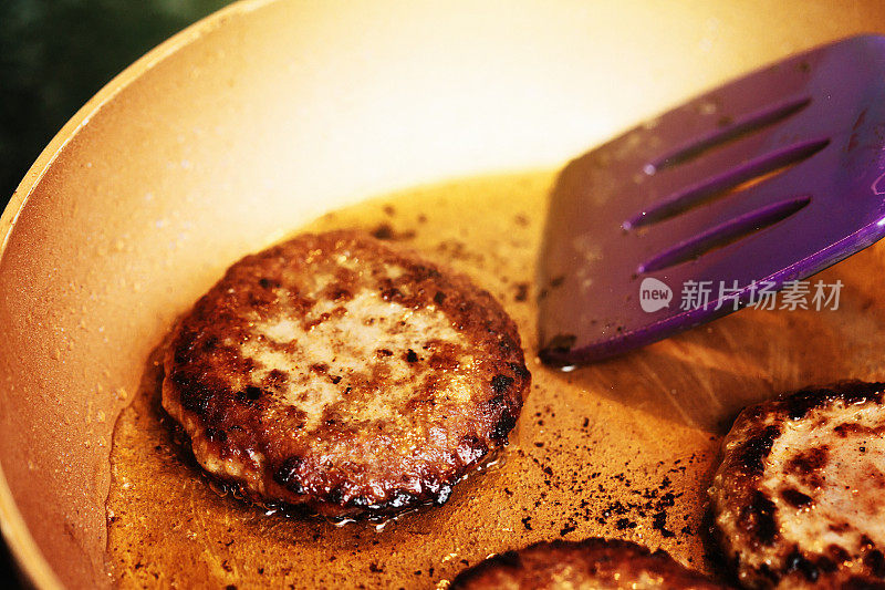 用铲子在煎锅里翻熟的汉堡肉饼