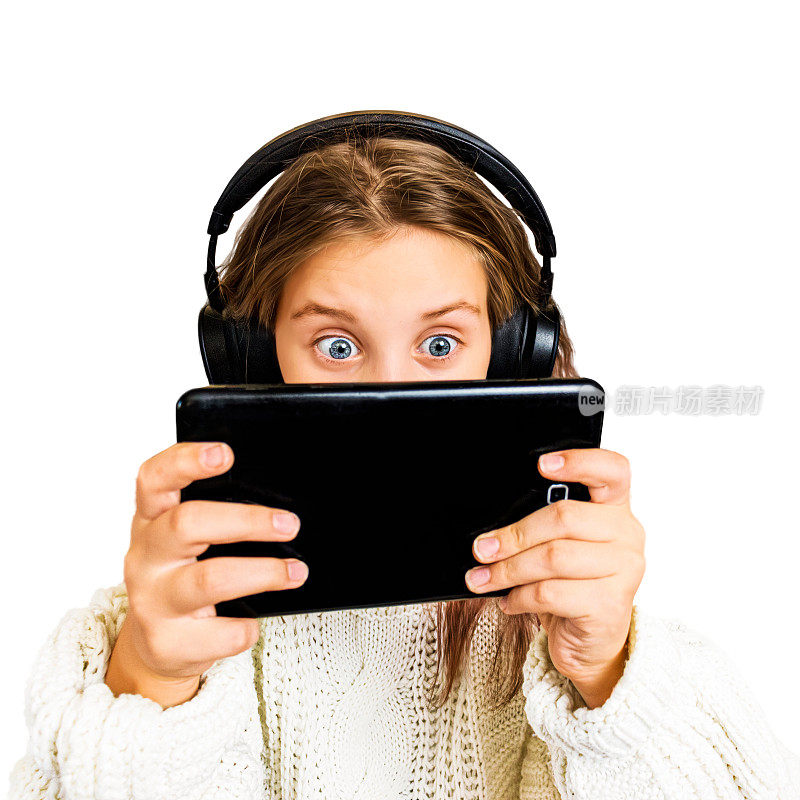 十几岁的女孩戴着耳机，热情地玩着，看着白色背景的平板电脑，