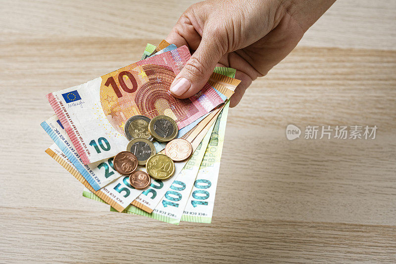 金融概念:手持欧元纸币和硬币