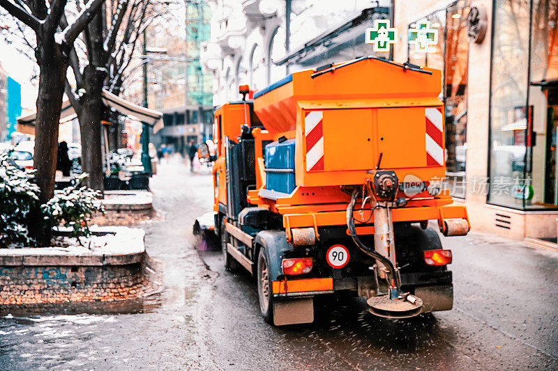 吹雪机清理城市街道的人行道，路过店面