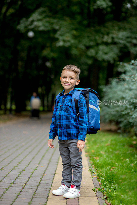 一个带着蓝色背包的学龄男孩去公园上学