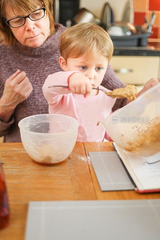 奶奶看着孙女舀出一团蛋糕混合物，准备烤蛋糕