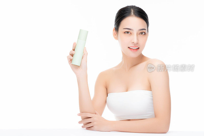 美丽的亚洲女性模特拿着化妆品瓶微笑美丽的亚洲女性展示护肤瓶产品美丽的脸身体肖像隔离在白色背景复制空间用于广告