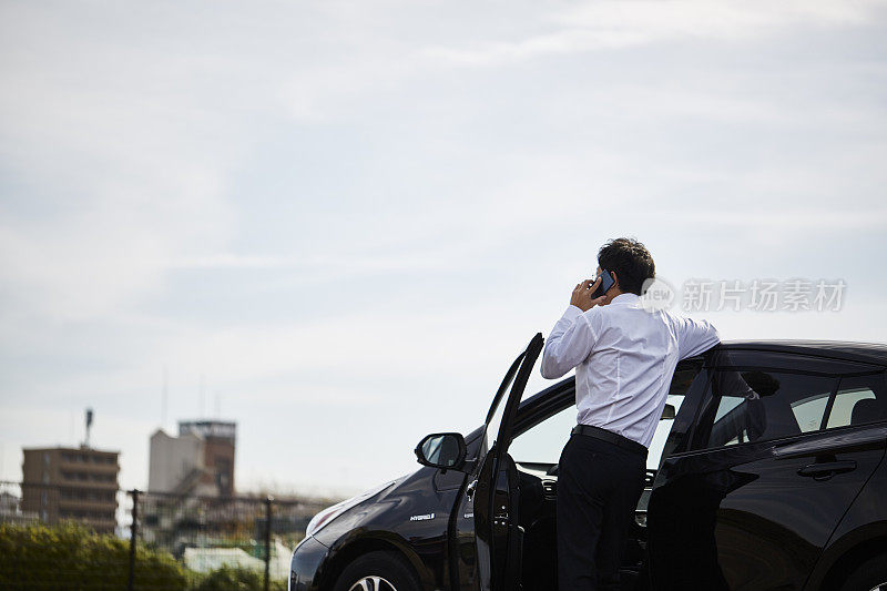 男人站在他的车旁边打电话的背影