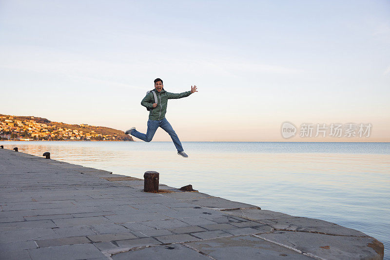 清晨，兴奋的男游客在海边跳跃