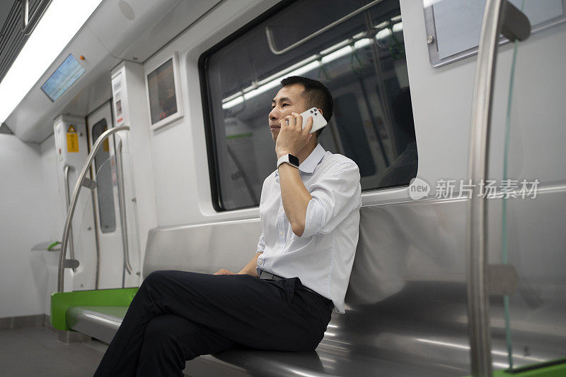 一个亚洲人在地铁里打电话