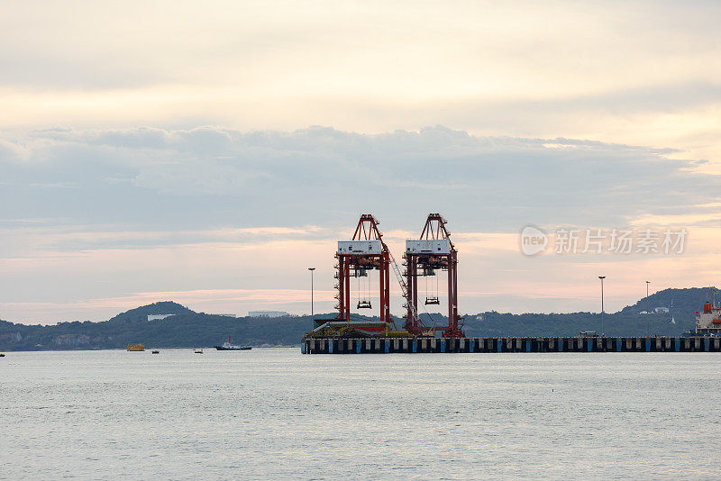 傍晚在港口、海上、河码头。工业起重机的轮廓。港口风景。明亮的夕阳，剪影动力起重机在海港，进出口的概念。