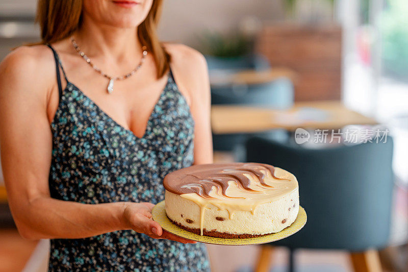 一个女人拿着并展示一个装有蛋糕的盘子的特写