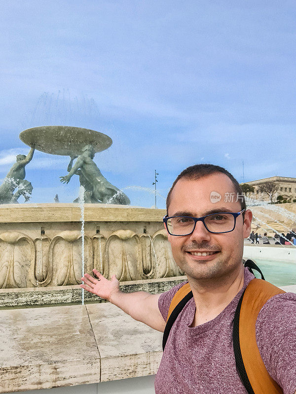 一名年轻人在马耳他瓦莱塔的Tritons喷泉前自拍