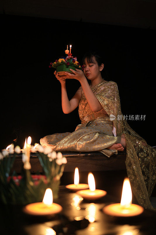 一位可爱的年轻女子穿着泰国传统服装，手拿“克拉通”向水神祈祷