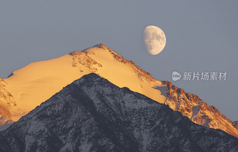 山景与几乎满月。哈萨克斯坦大阿拉木图峡谷的苏联峰和斯卡利斯峰，天山的阿拉托山脉