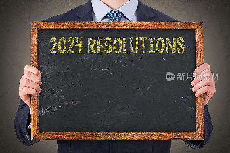 商务人士在黑板背景上书写2024年新年决心