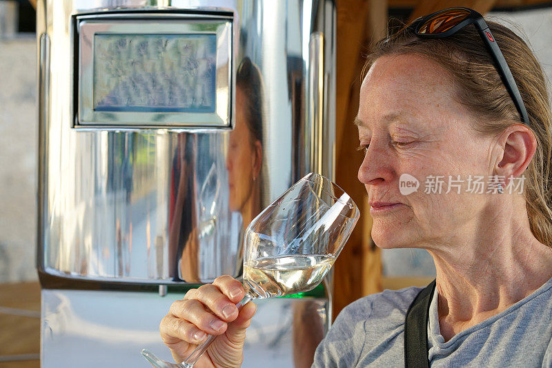 图为高级女性在户外品酒现场，正在喝白葡萄酒。