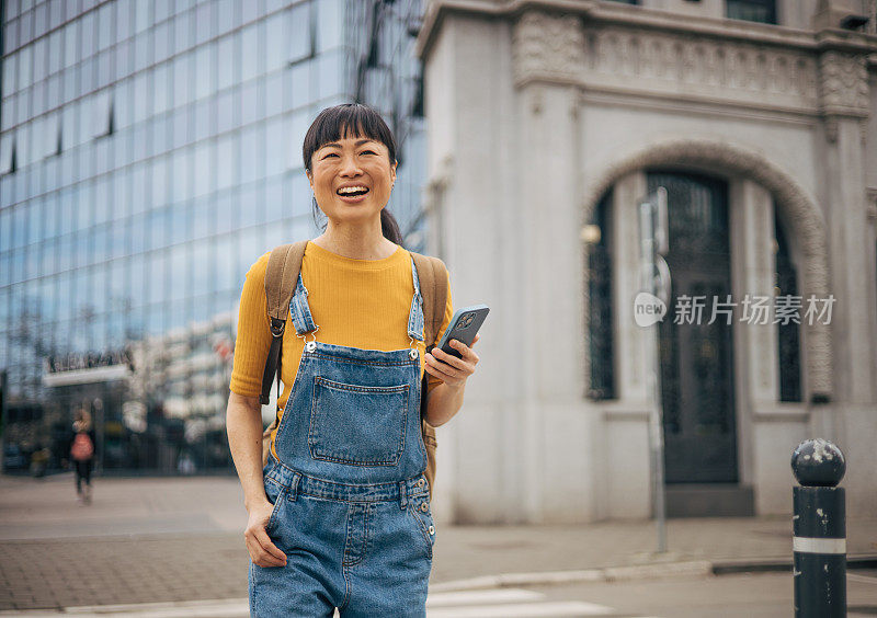 一个女人用手机在城市里走来走去