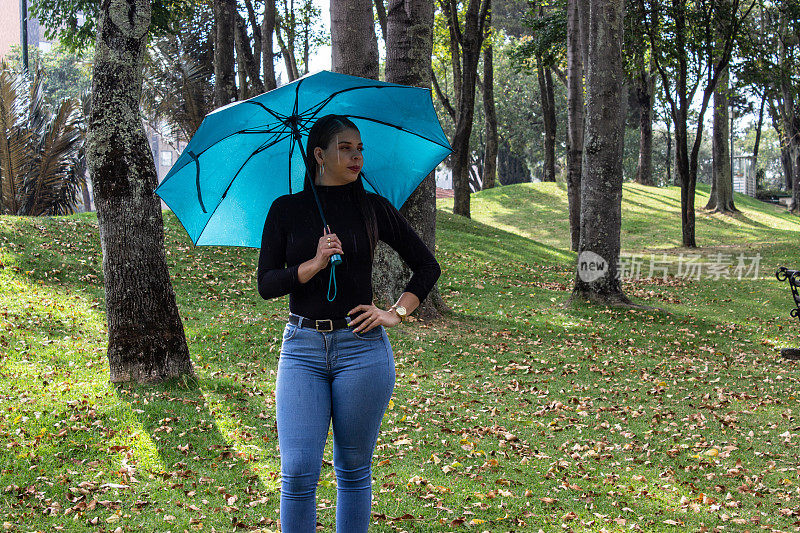 公园里一个漂亮的年轻女子在森林里撑着一把伞